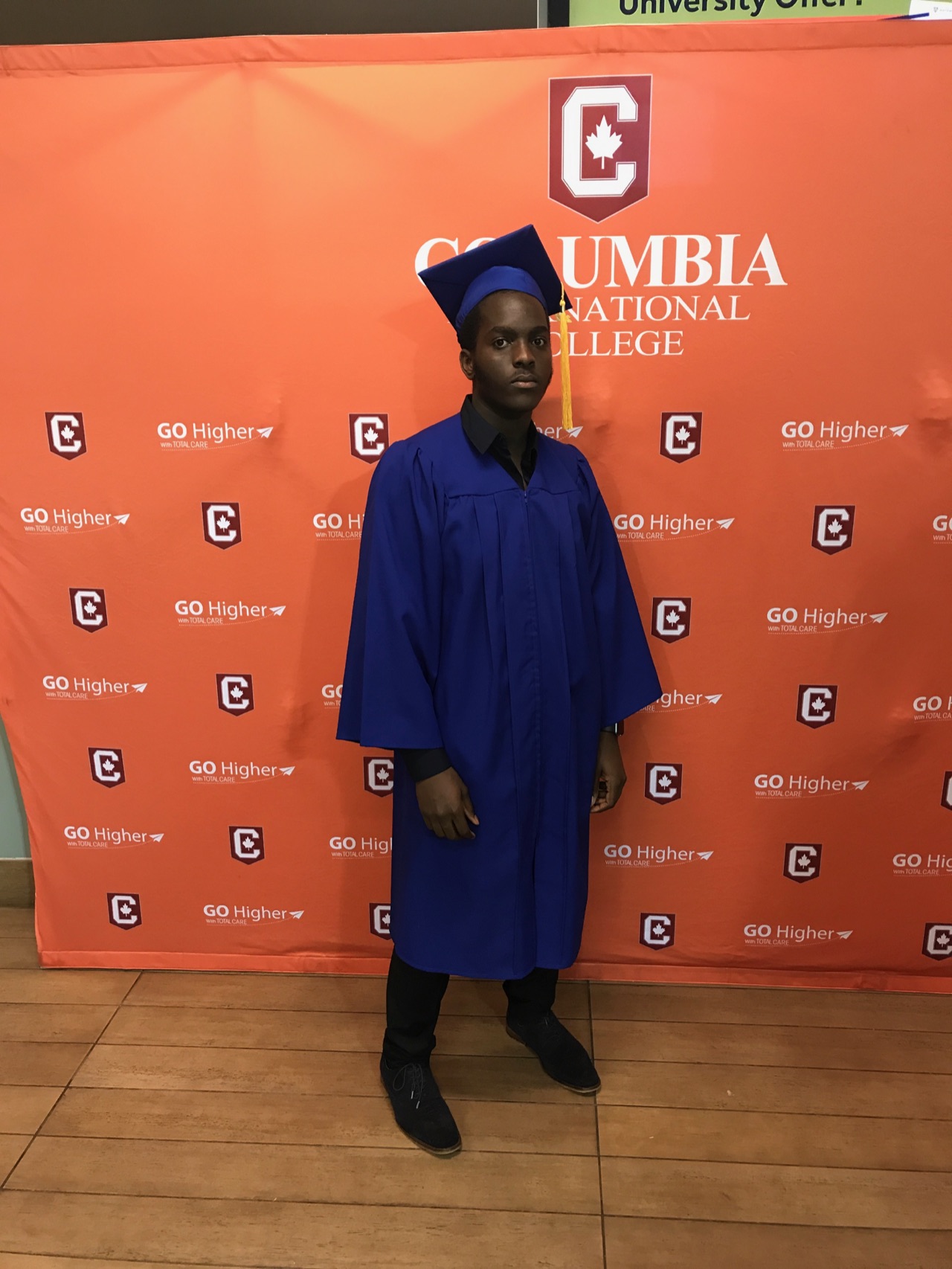 Clinton in a blue graduation gown in front of the Columbia International College backdrop in 2017.